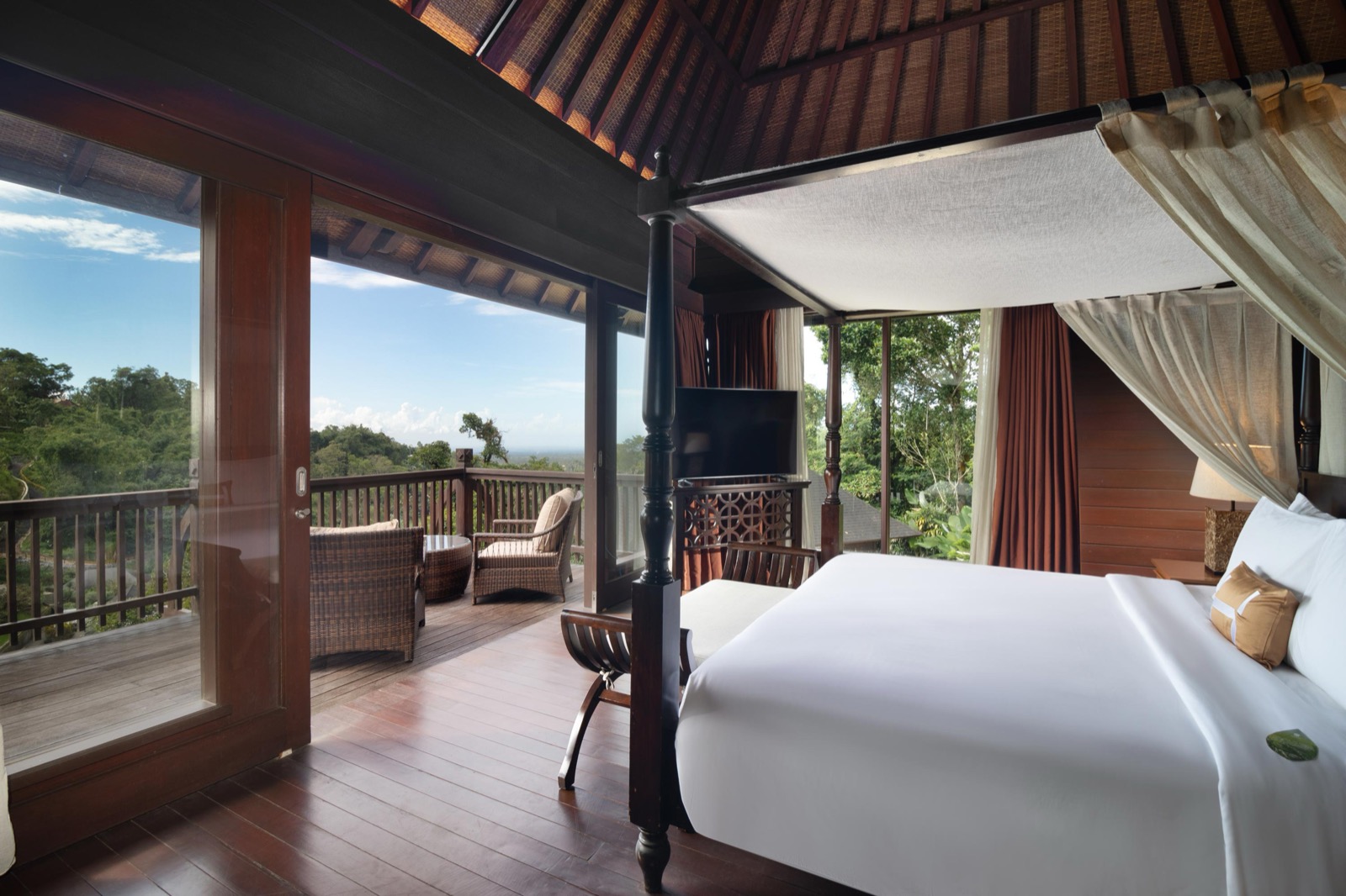 Guest room with a four-poster bed opening onto a timber deck in the treetops at HOMM Saranam Baturiti, Bali