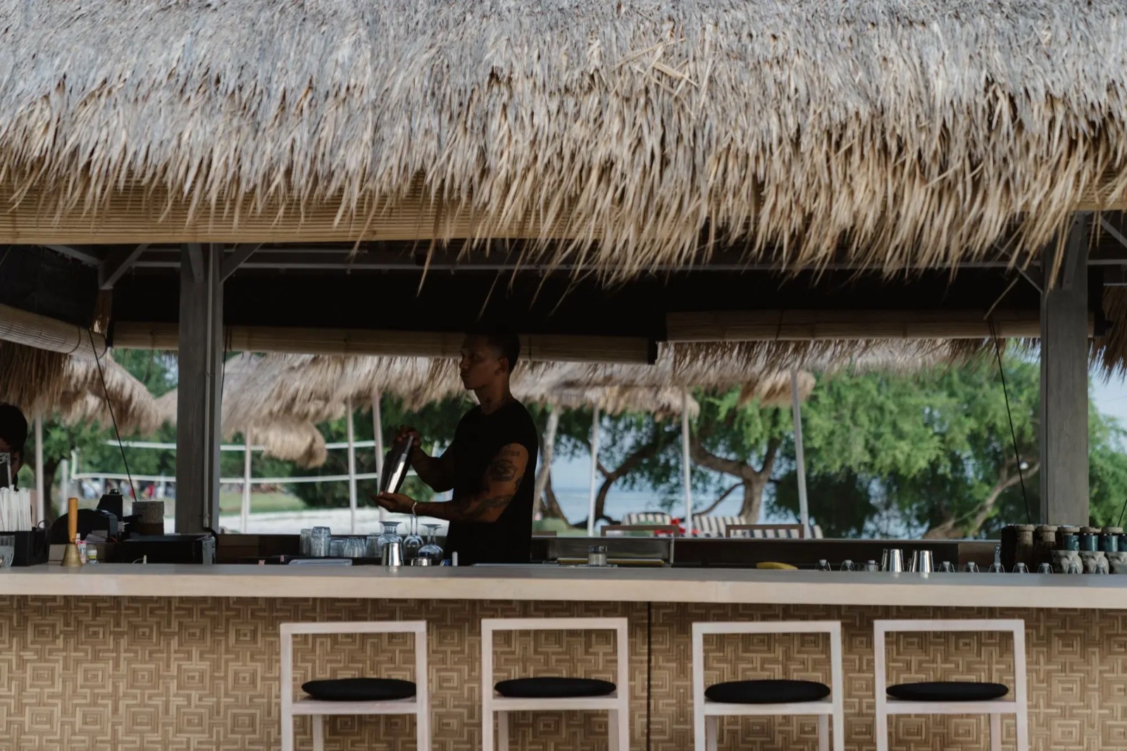 Bartender mixing drinks at the thatched beachfront bar at Hotel Lumi Gili Trawangan