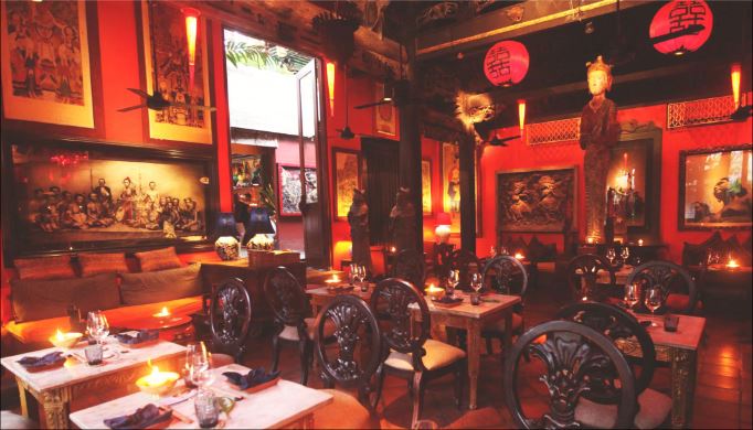 The crimson Bale Sutra antique dining room lit by candles at Hotel Tugu Bali, Canggu