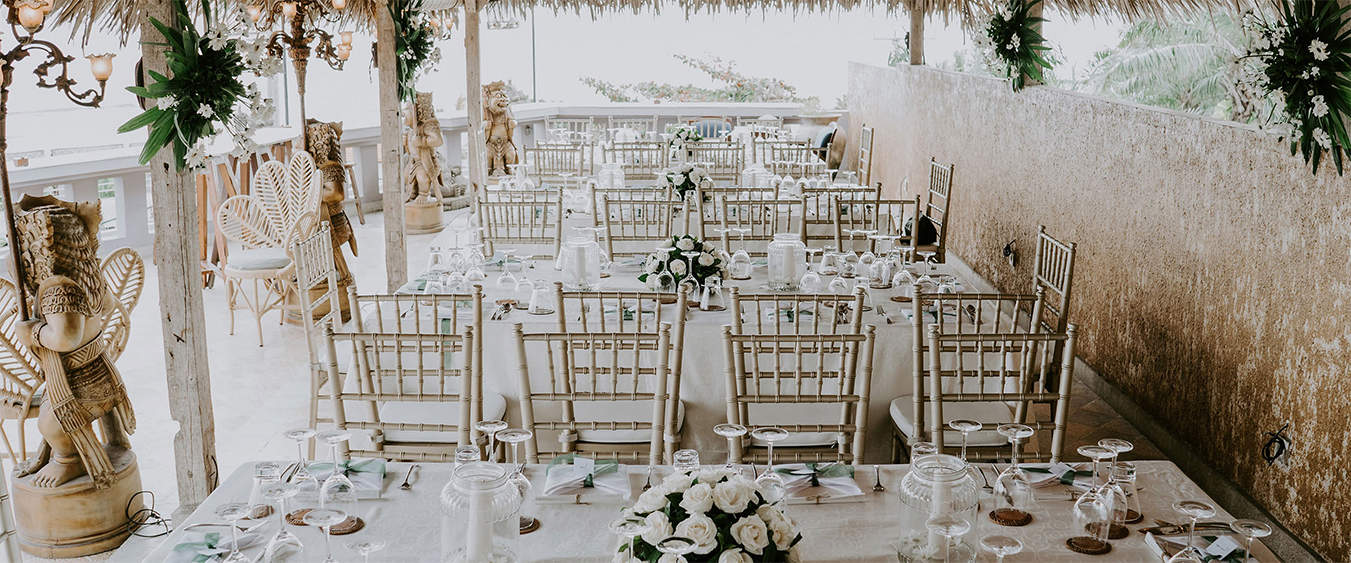 Reception dinner under a thatched terrace pavilion with antique statues and an ocean view at Hotel Tugu Bali, Canggu