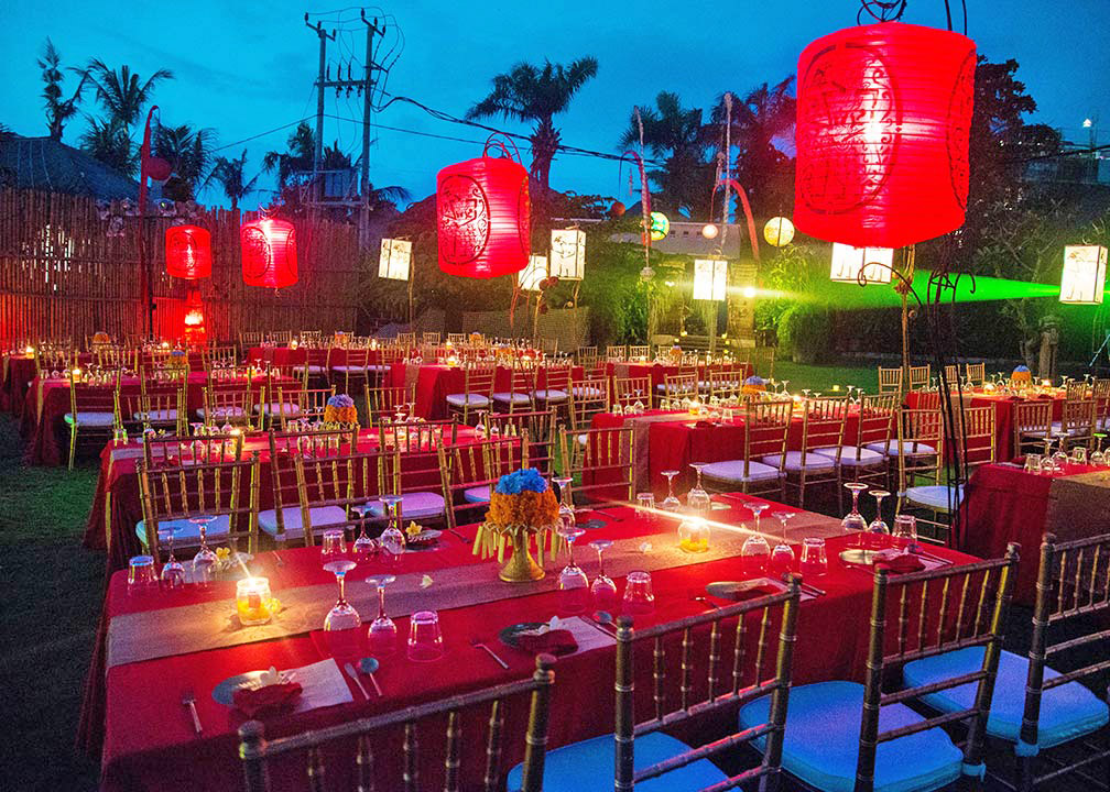 Dramatic garden banquet with red tablecloths and glowing red lanterns after dark at Hotel Tugu Bali, Canggu