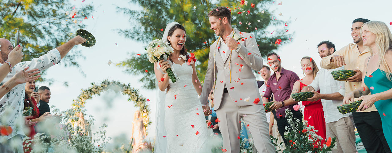 Newlyweds walking through a shower of petals thrown by guests after their ceremony at Hotel Tugu Lombok on Sire Beach, Lombok