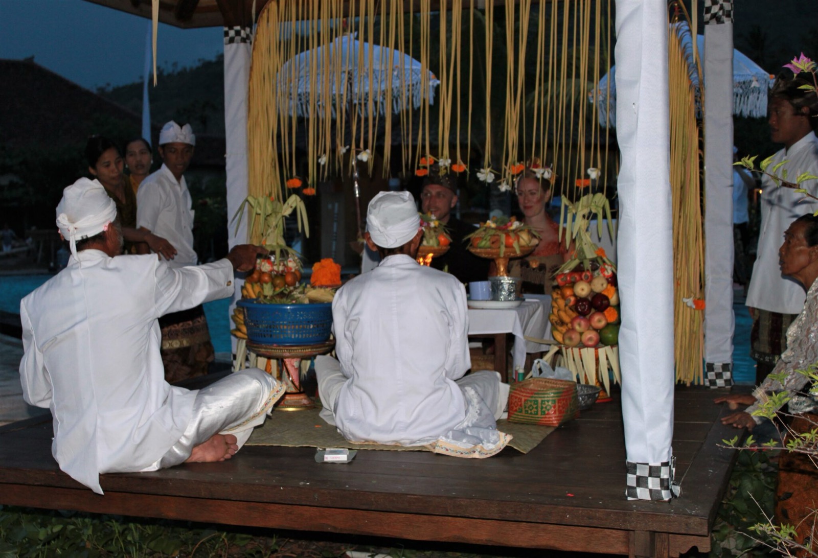 Balinese priests seated with offerings at the ceremony bale, the couple behind them, at Hotel Uyah Amed & Spa Resort in Amed, east Bali