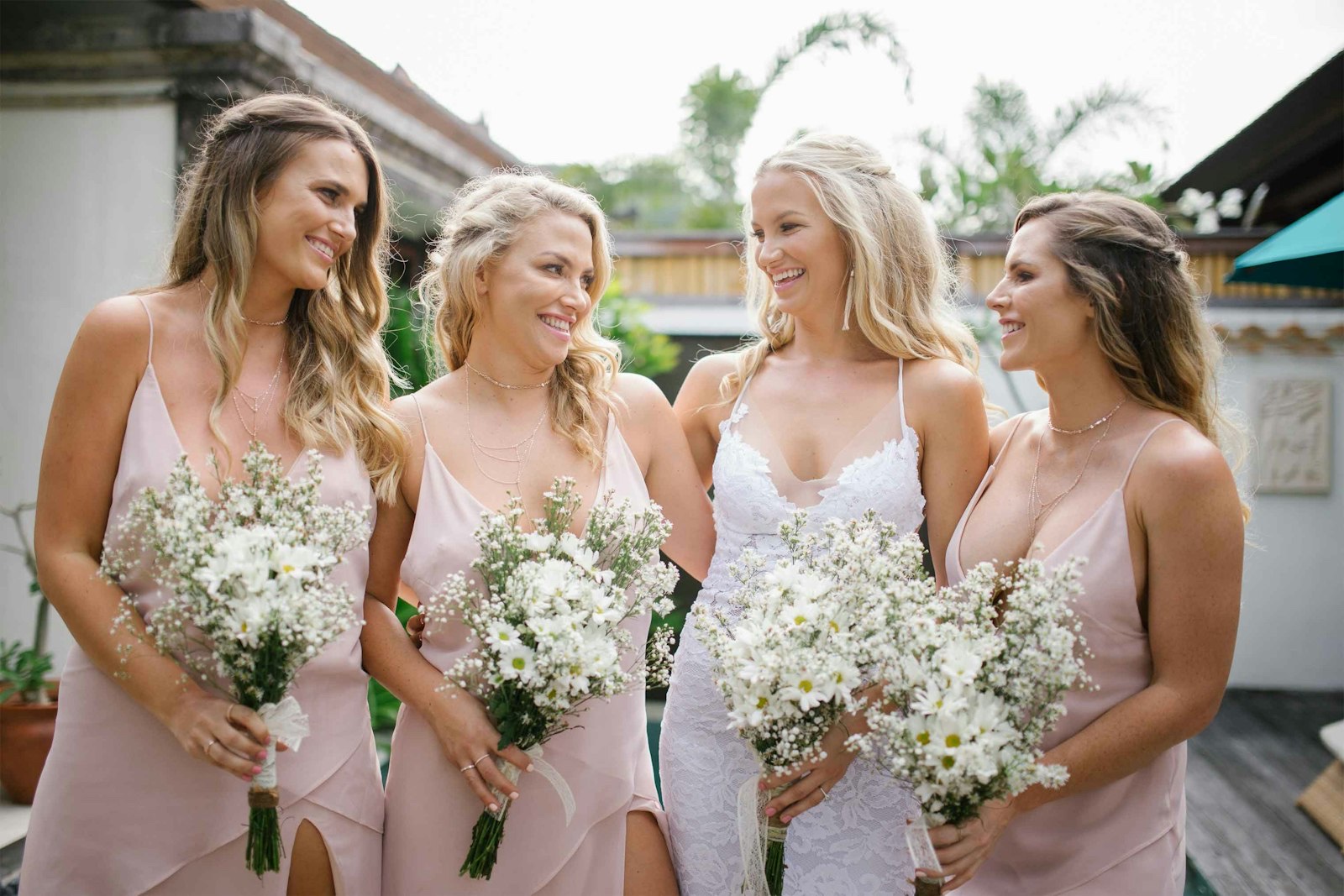 Bride with three bridesmaids in blush dresses holding daisy and gypsophila bouquets at Hotel Vila Ombak, Gili Trawangan