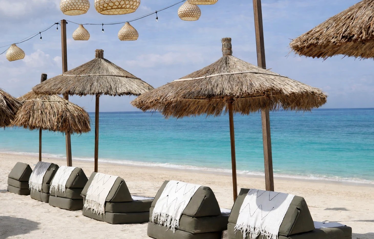 Straw umbrellas and loungers on the white sand of Jungut Batu beach at Indiana Kenanga, Nusa Lembongan, Bali