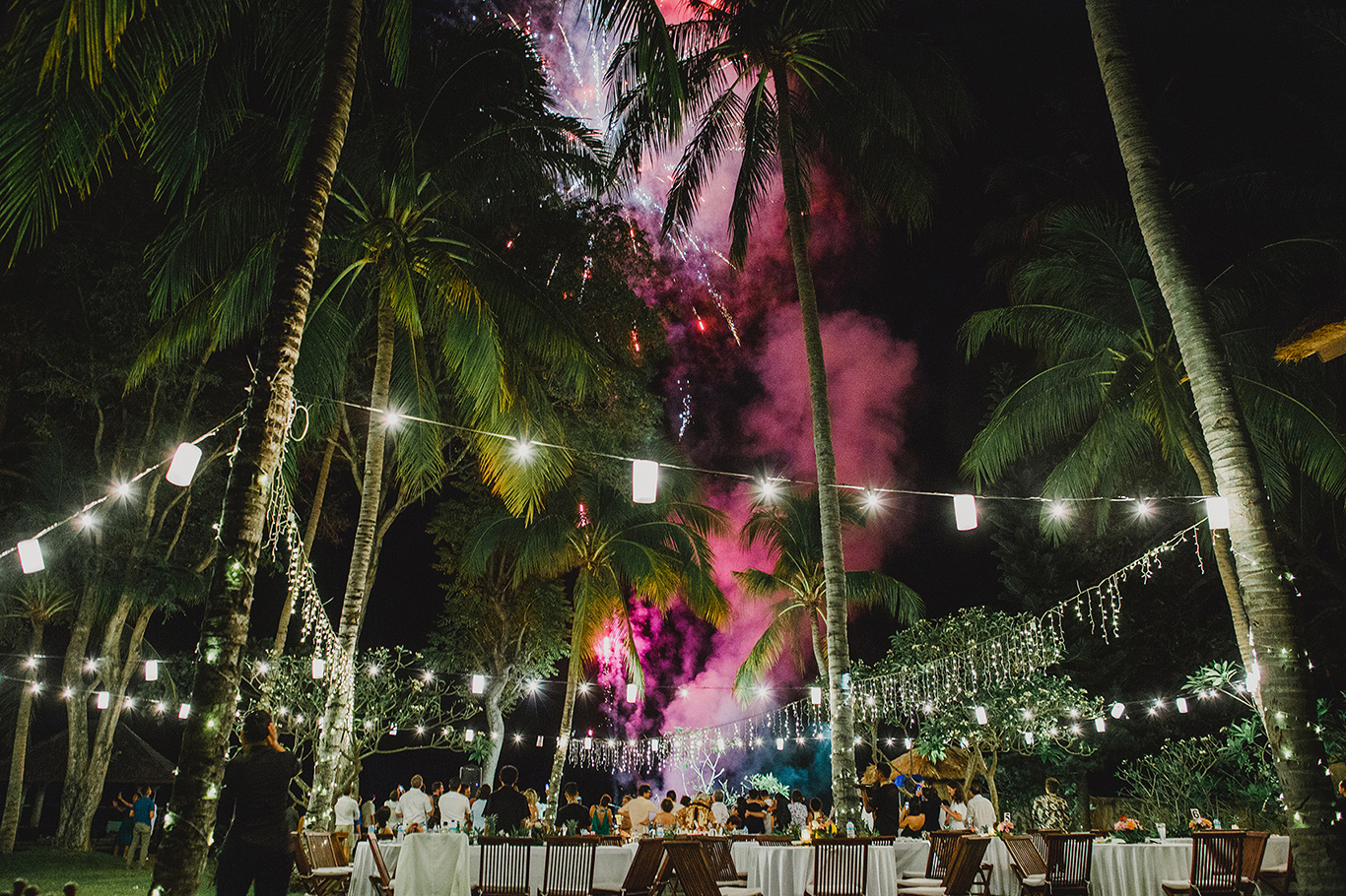 Fireworks over a garden reception strung with festoon lights under the palms at Jeeva Klui Resort, Lombok