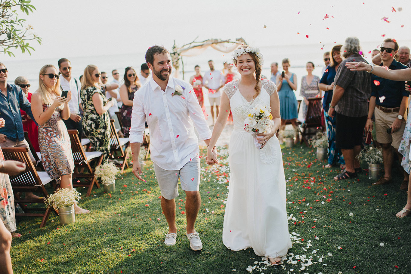 Newlyweds walking back down the lawn aisle through a shower of petals at Jeeva Klui Resort, Klui Beach