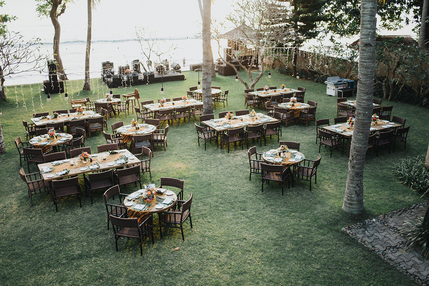 Reception tables laid on the garden lawn facing the sea with a stage set up on the sand, Jeeva Klui Resort, Lombok