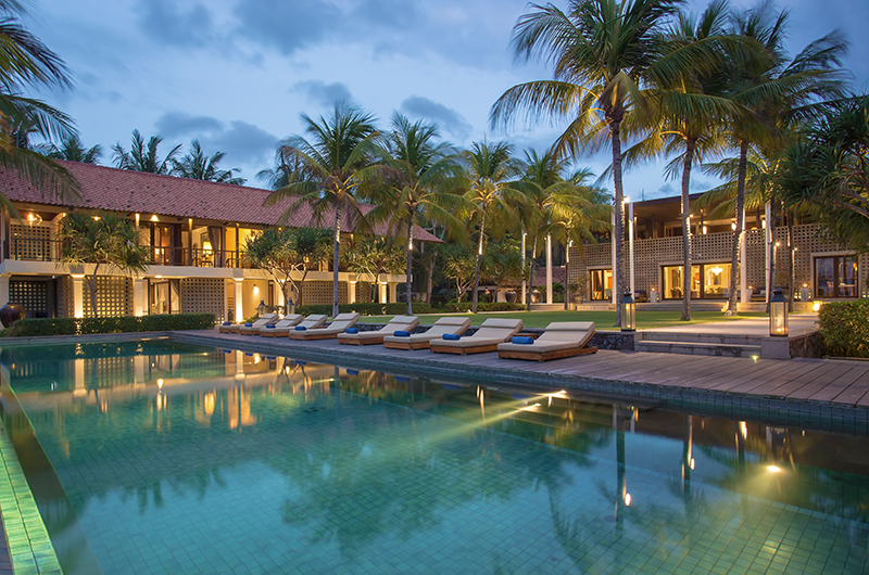Jeeva Saba estate lit at dusk, the pool reflecting the pavilions and palms on the Saba Beach frontage