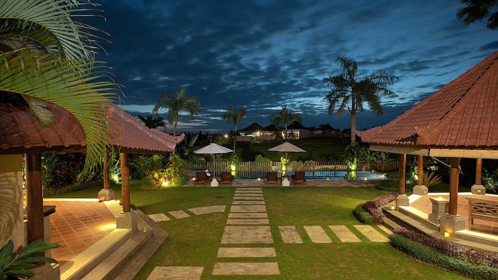 Aerial dusk view of The Junno Villa's garden and pool, with rice fields beyond