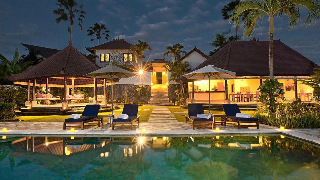 Twilight view of the pool, garden, and open-air pavilions at The Junno Villa in Canggu