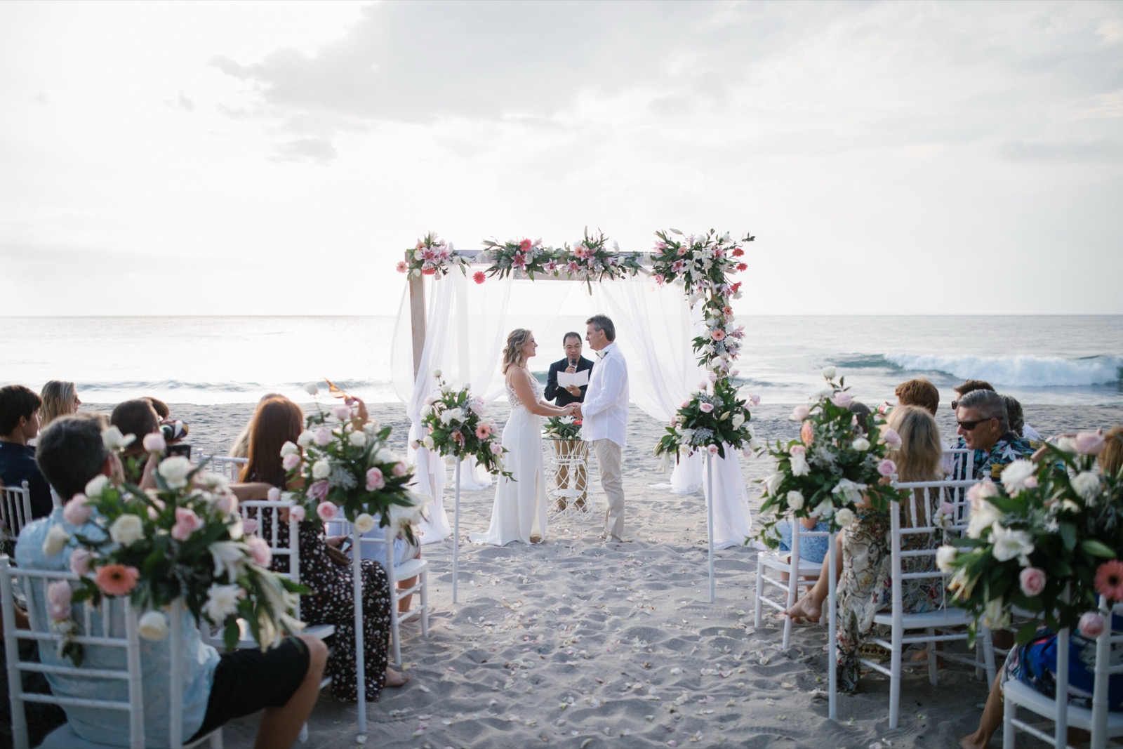 Guests watching a beachfront ceremony in front of the surf at Katamaran Resort Lombok on Lombok's west coast