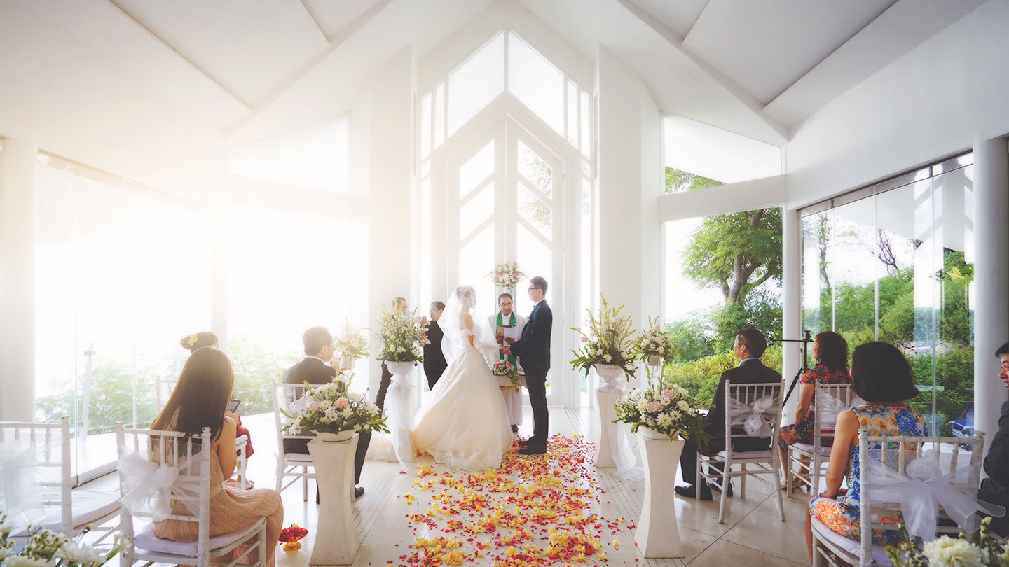 Ceremony inside the all-glass Mangsit wedding pavilion with a petal aisle and seated guests at Katamaran Resort Lombok