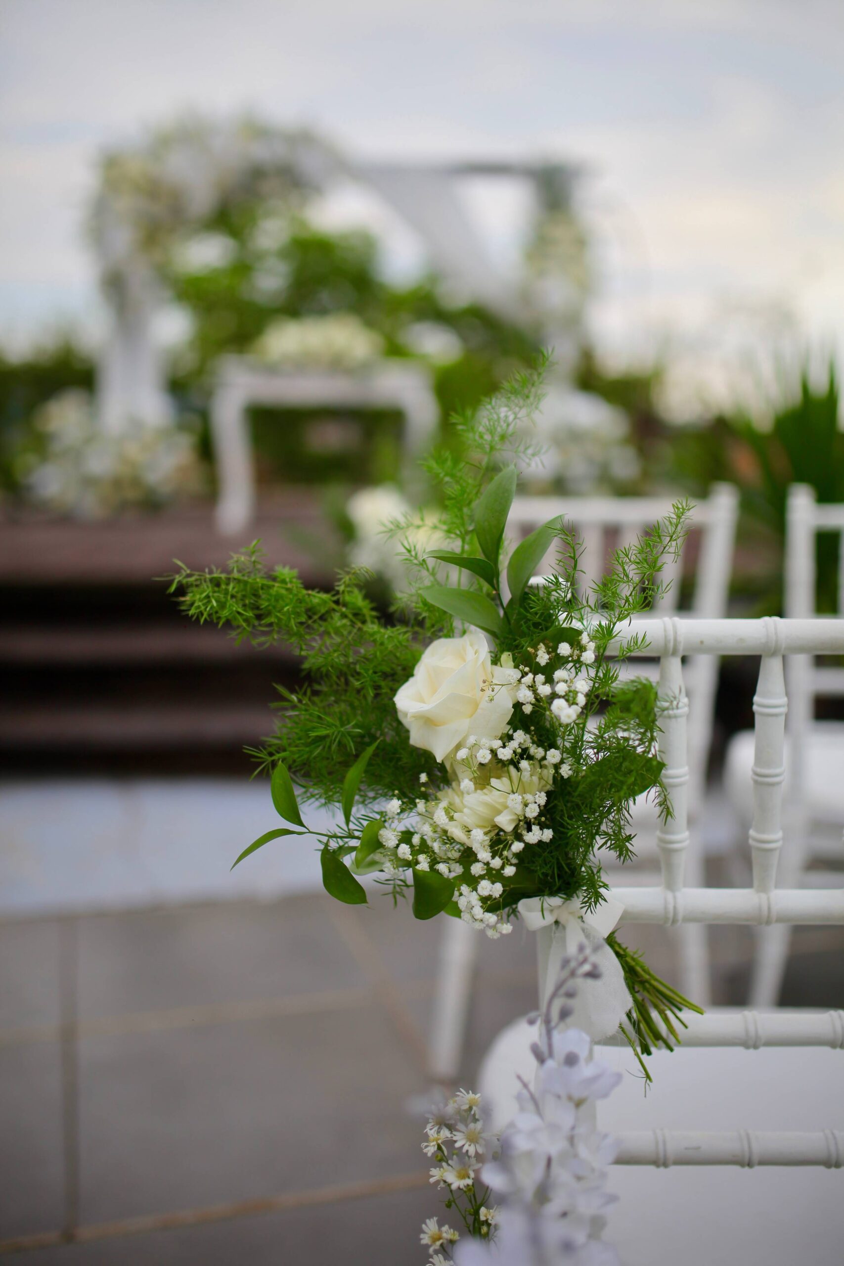 A styled wedding ceremony setup at The Leaf Jimbaran, with a floral aisle and arch amid the resort's tropical villa gardens