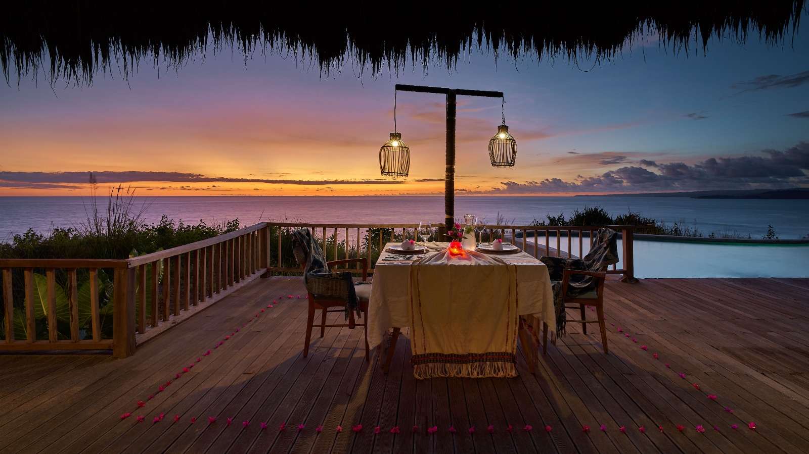 Candlelit dinner for two on a timber deck above the ocean at sunset at Lelewatu Resort Sumba, Sumba
