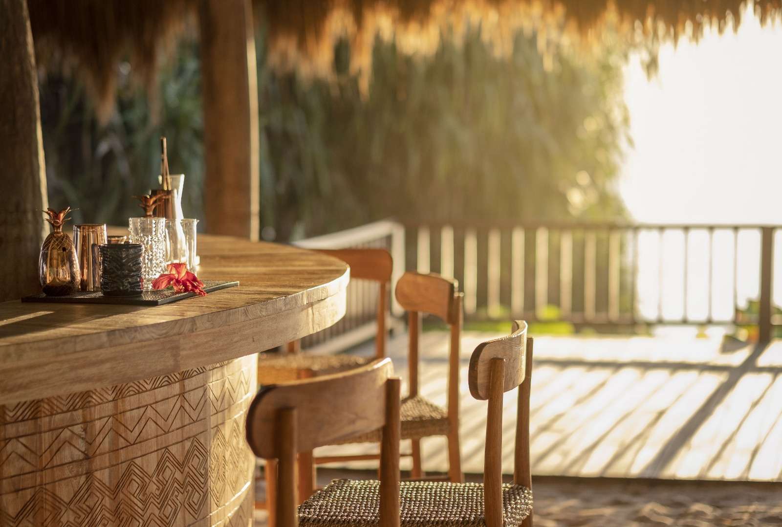 Carved timber bar counter with woven-seat chairs under a thatched roof at Lelewatu Resort Sumba, Sumba