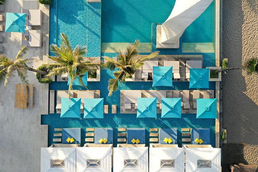 Aerial view of the resort pool area with palm trees and beach access at Lv8, Canggu