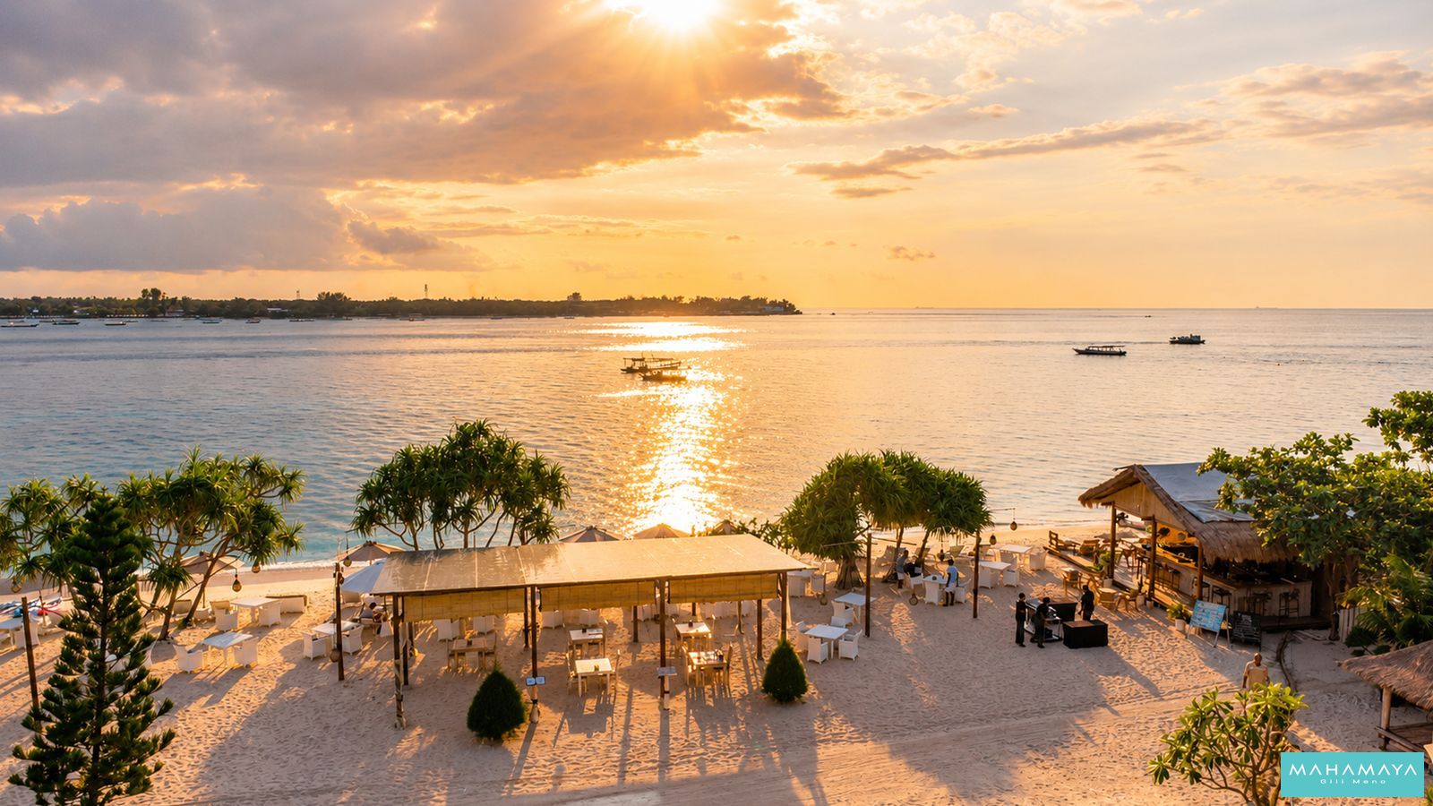 Sunset over the water from the beach dining pavilion and tiki bar at Mahamaya Gili Meno, with Gili Trawangan on the horizon