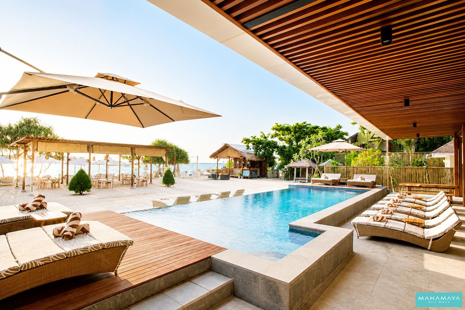 Pool and beach loungers running down to the white sand and sea at Mahamaya Gili Meno, on Gili Meno off Lombok