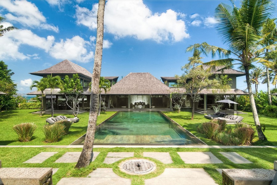 Mahatma House villa exterior with its long reflecting pool, palm trees, and open-plan pavilions in Seseh, Canggu