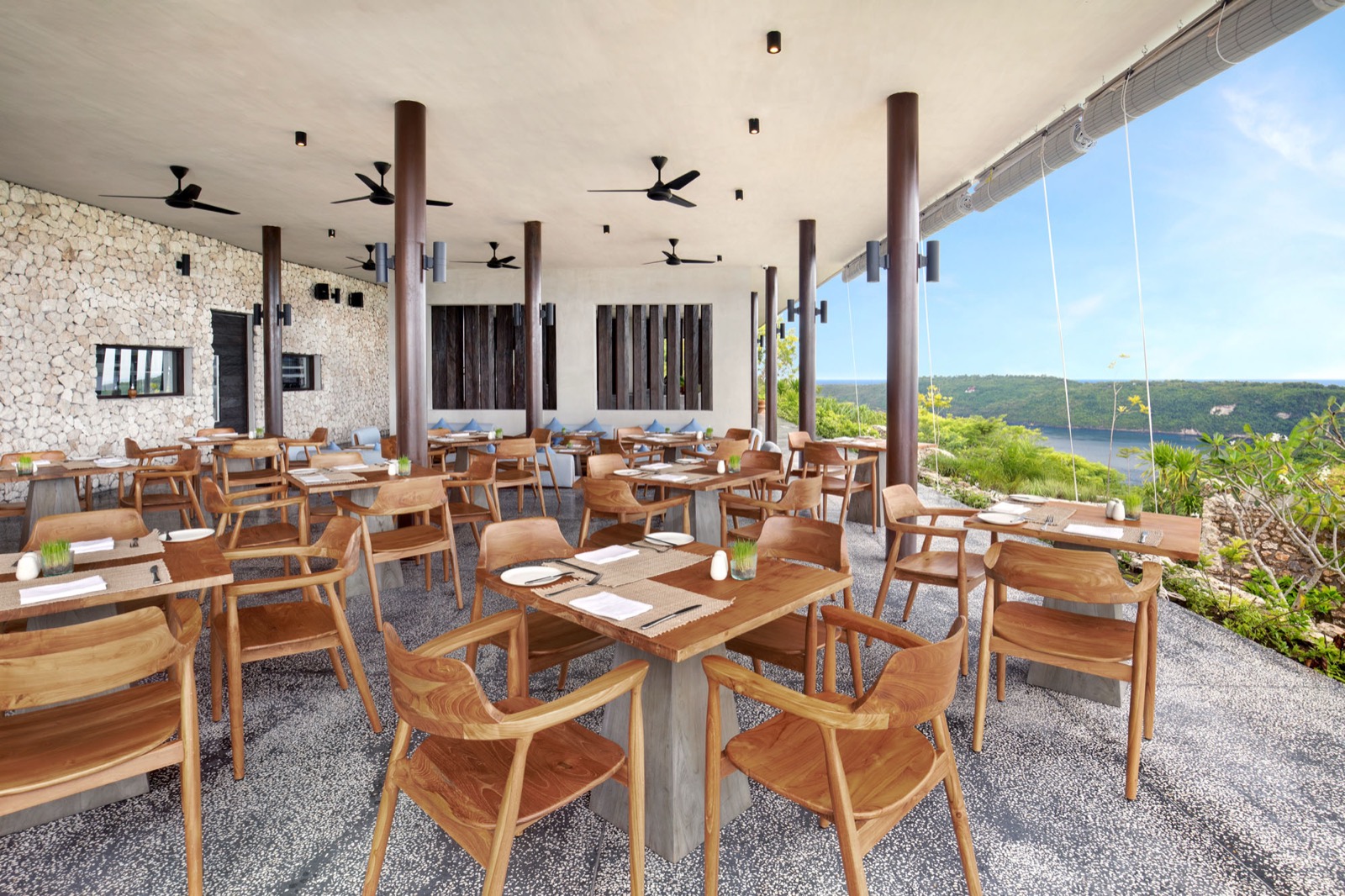 Kowhai restaurant terrace with teak tables and a view over Gamat Bay at MAUA Nusa Penida, Bali
