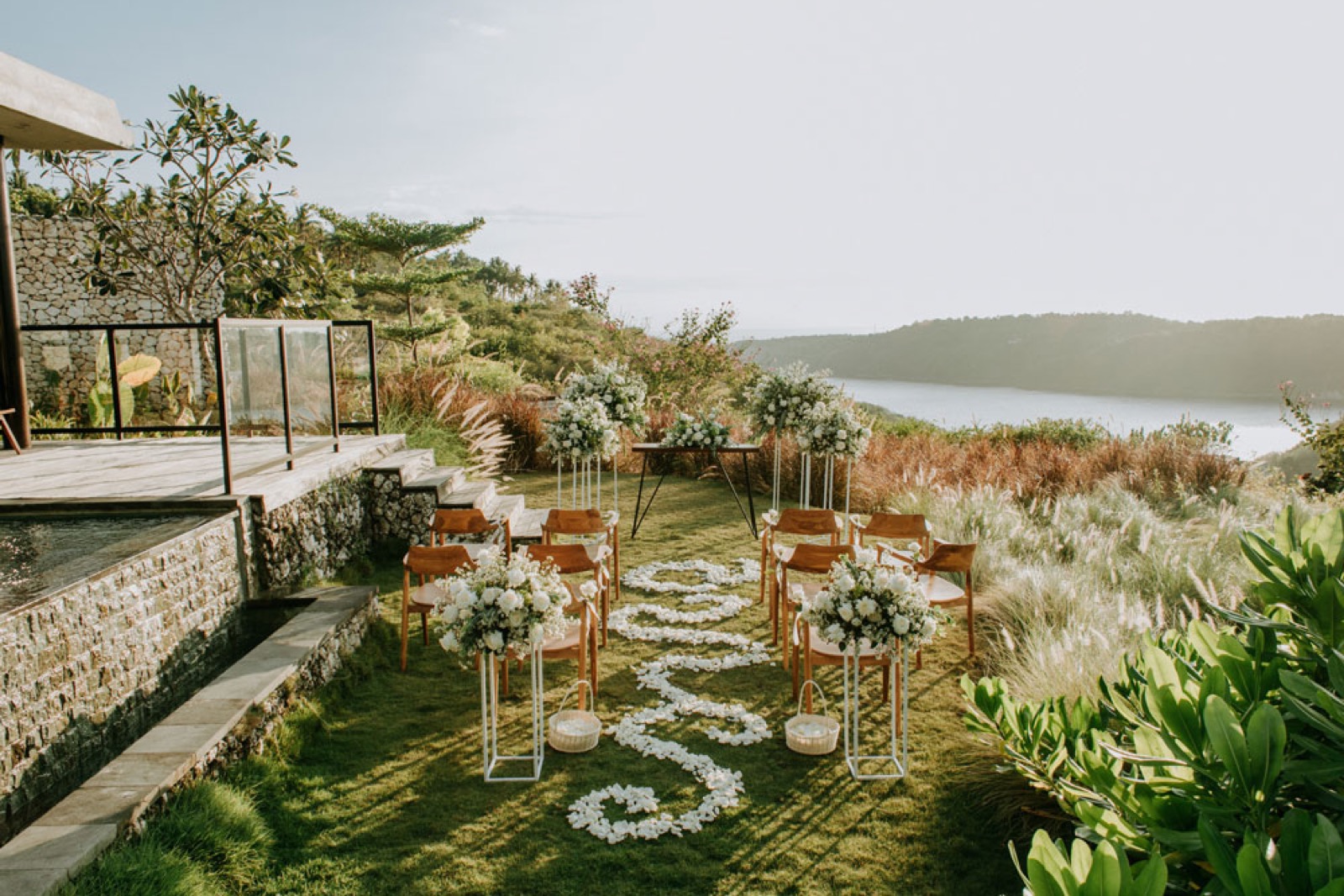 Wedding ceremony circle of petals and teak chairs on the lawn above Gamat Bay at MAUA Nusa Penida, Bali