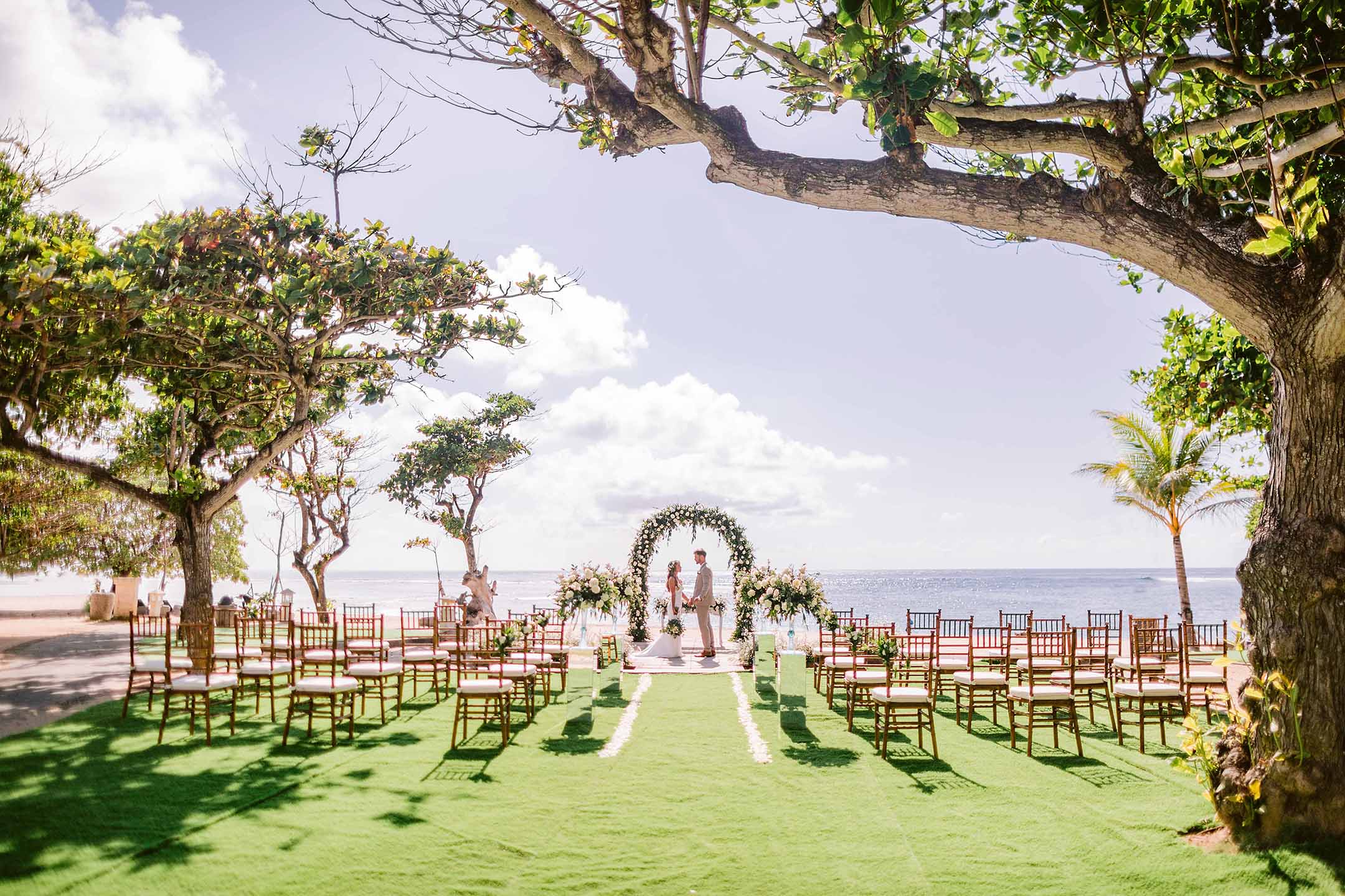 An outdoor beachfront wedding setup at Merusaka Nusa Dua, Bali, with the Indian Ocean beyond