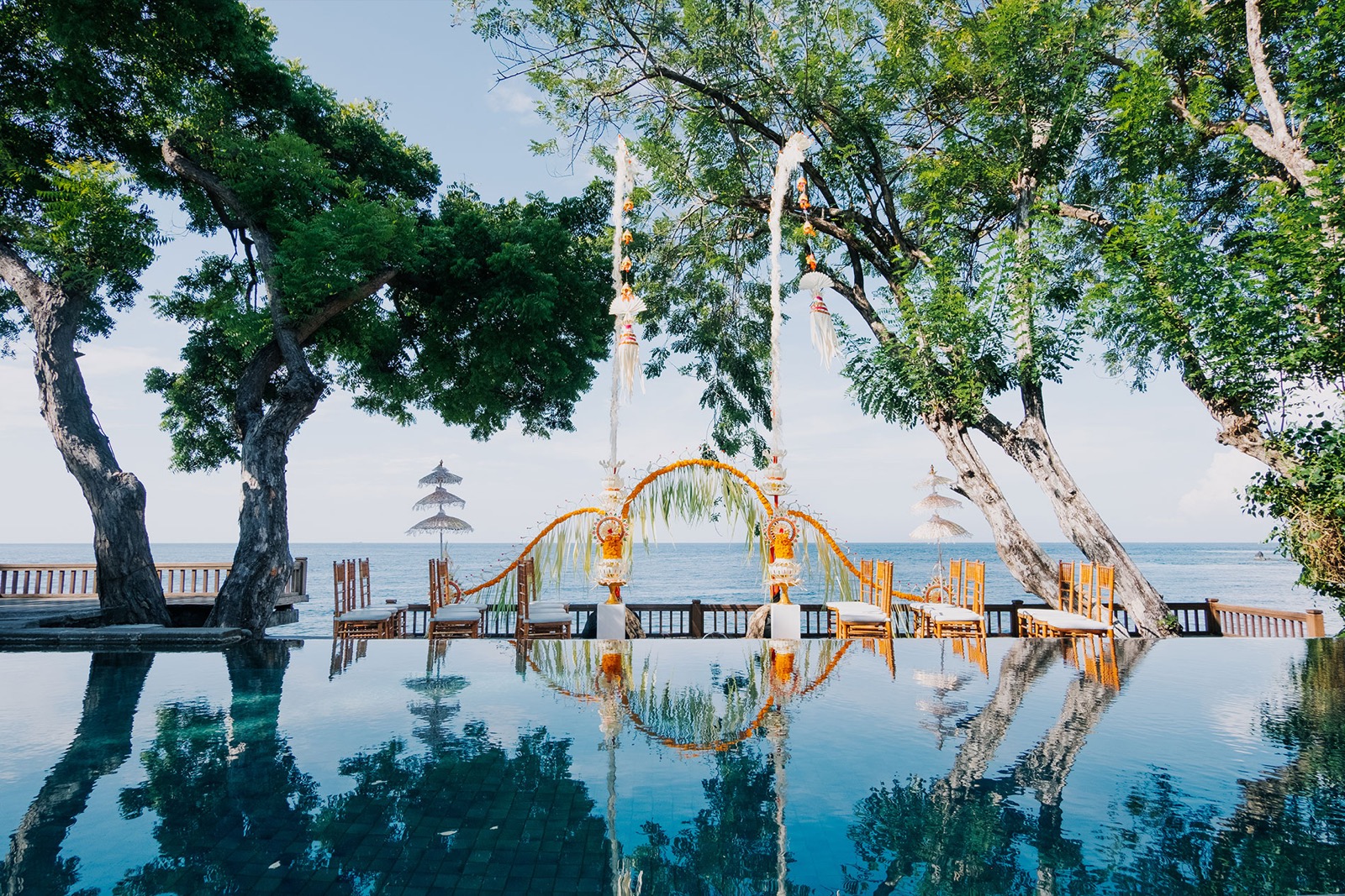 Balinese wedding arch of marigolds and palm leaf reflected in the infinity pool above Tulamben Bay at Mimpi Resort Tulamben in northeast Bali