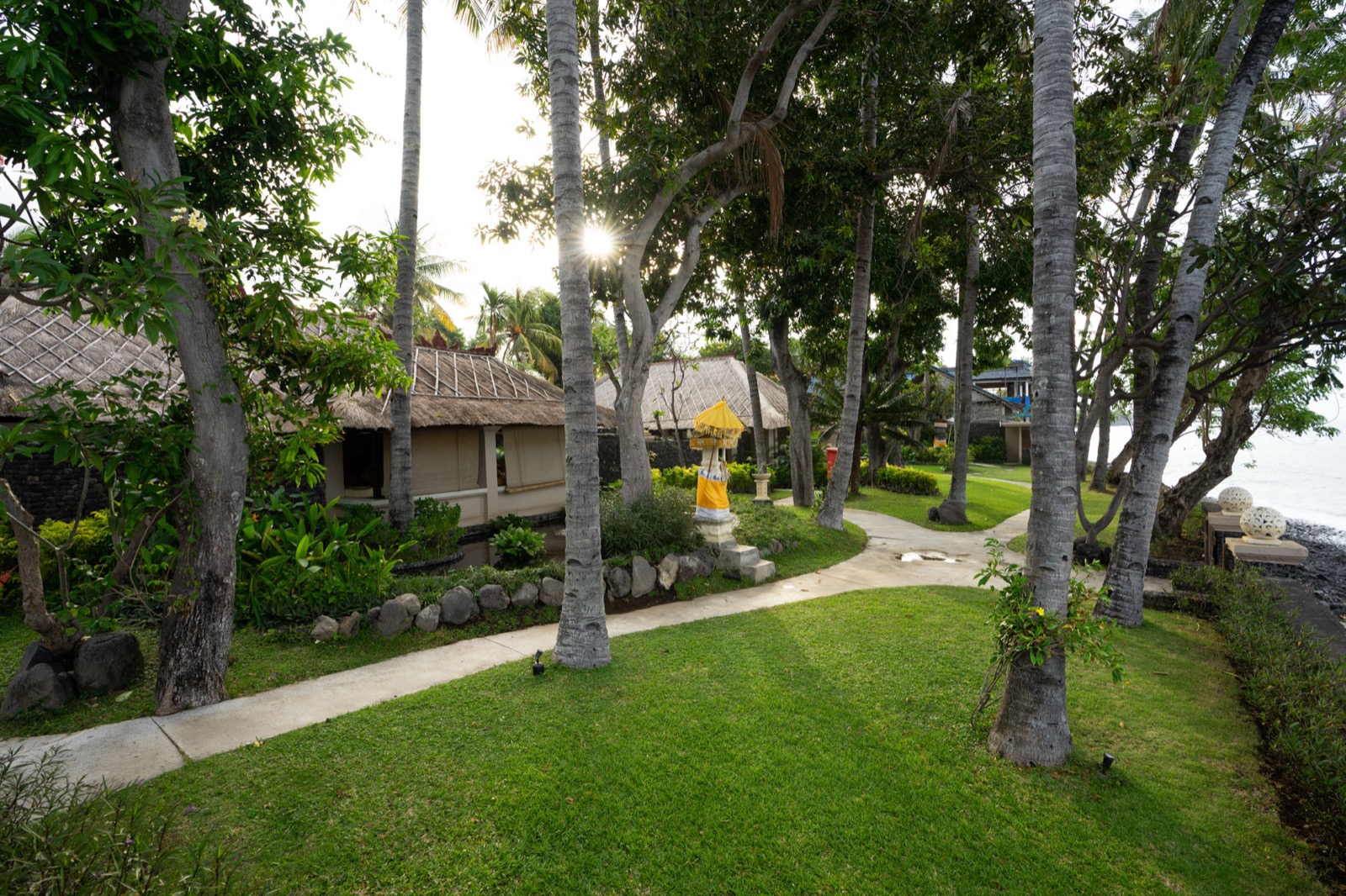 Thatched villas, coconut palms and lawns running down to the shore at Mimpi Resort Tulamben in northeast Bali