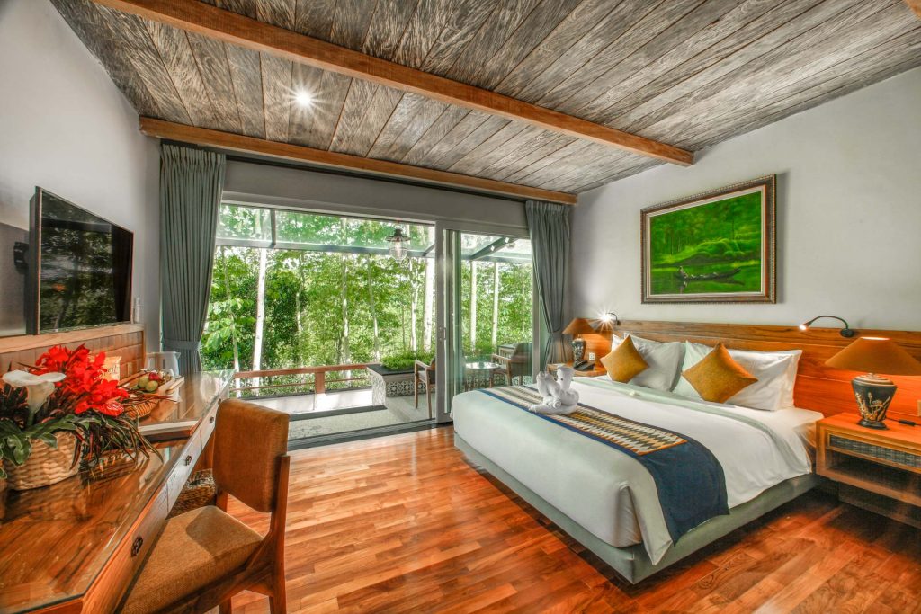 Guest room with a timber plank ceiling opening onto a balcony in the treetops at Munduk Heaven Luxury Villas, Bali