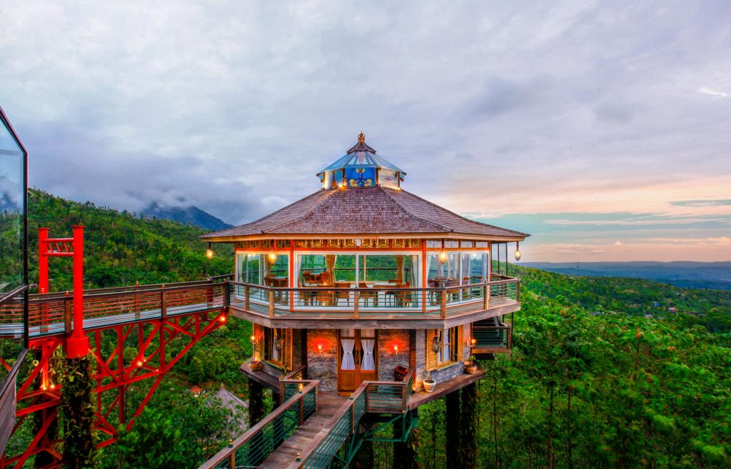 The round glass wedding chapel at Munduk Heaven Luxury Villas lit at dusk above the forest, reached by a bridge, Munduk, north Bali