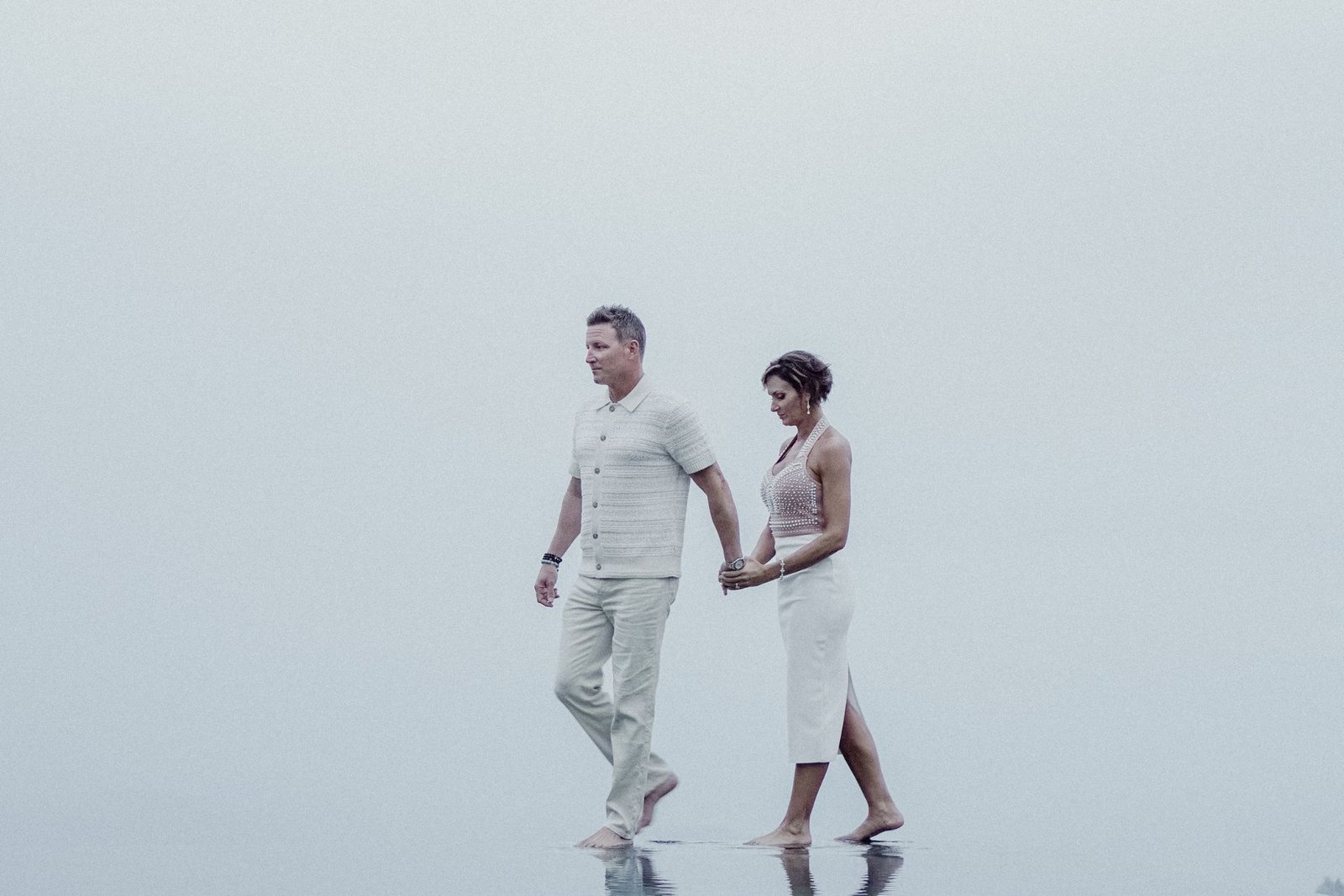Couple walking hand in hand across the infinity pool in thick highland cloud at Munduk Moding Plantation, north Bali