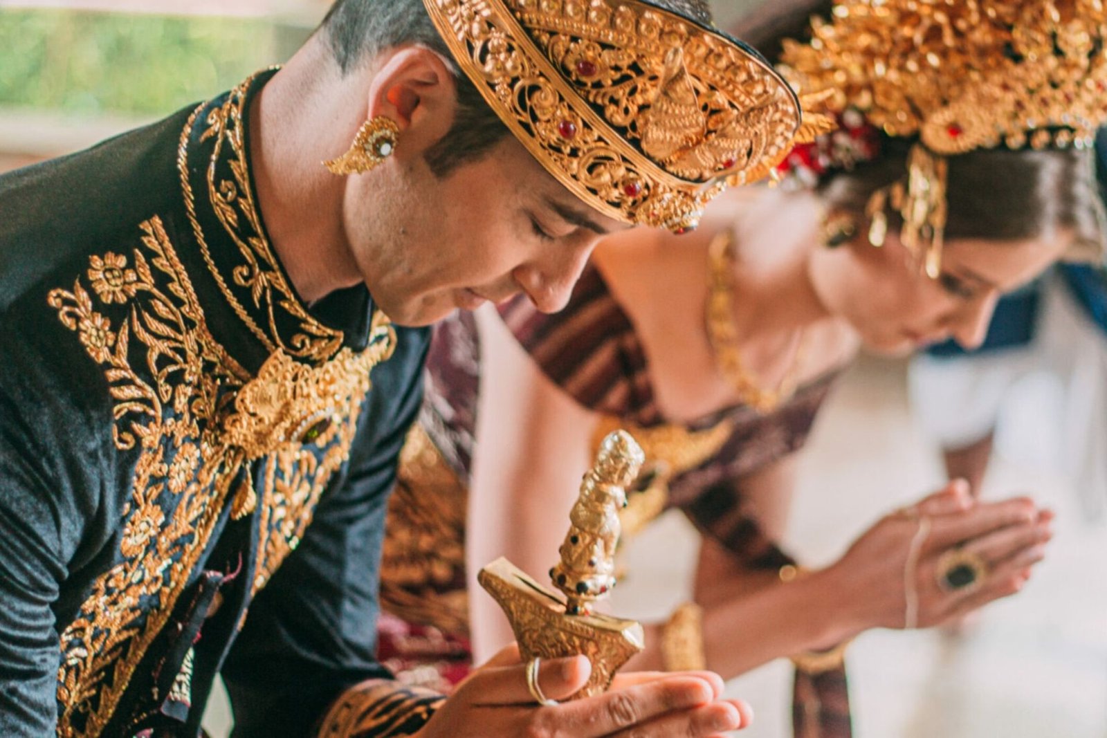 Close view of a bride and groom in Balinese ceremonial dress bowing in prayer at Munduk Moding Plantation, Bali