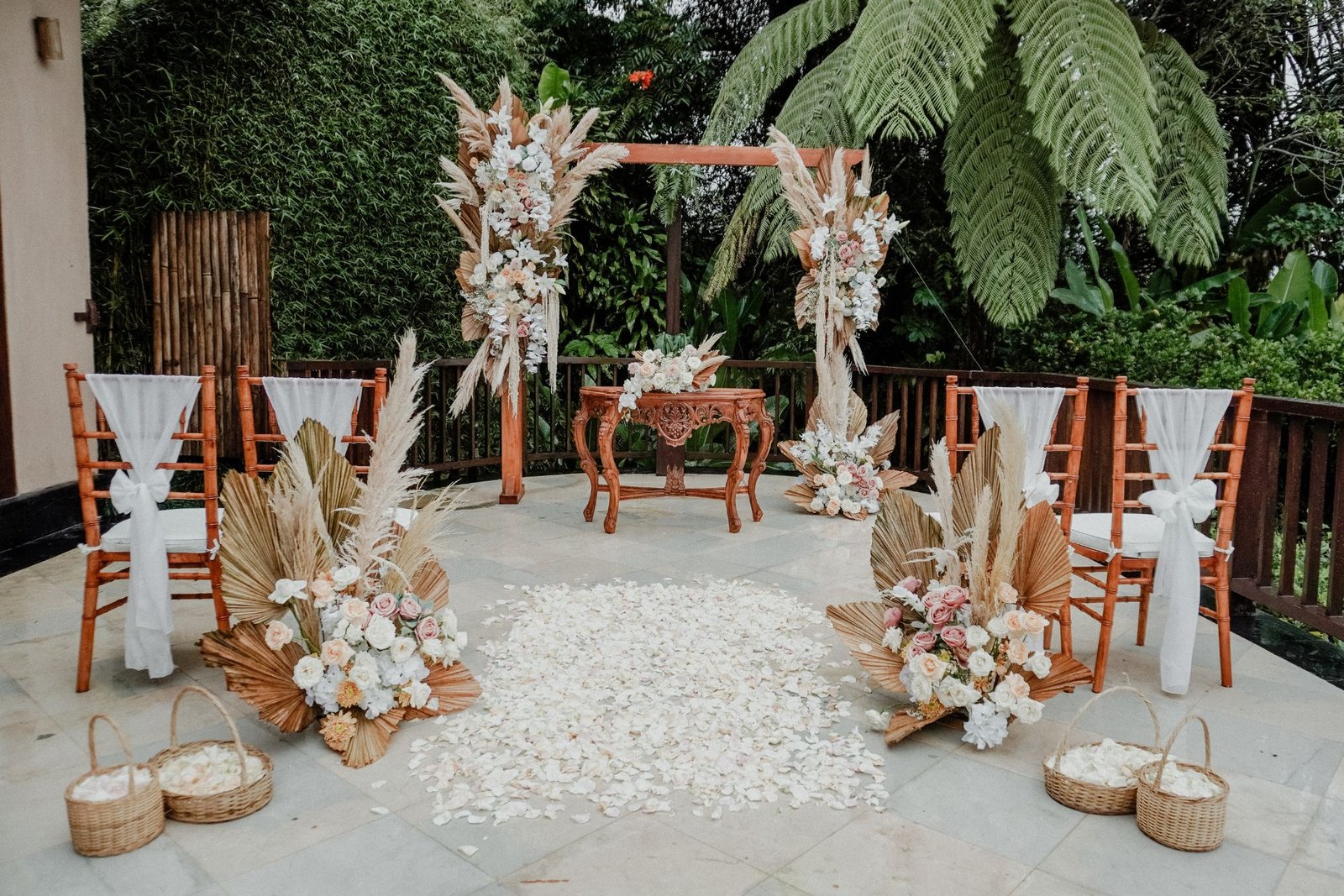 Ceremony deck set with a timber arch, pampas florals and chairs against tree ferns at Munduk Moding Plantation, Bali