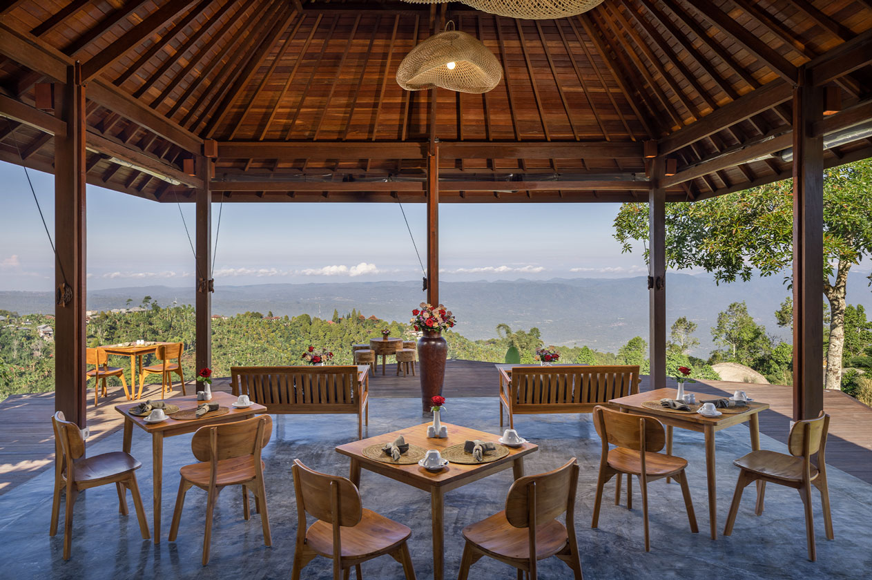 Open-sided timber pavilion restaurant set with tables above the hills at Munduk Tentrem, Munduk, Bali