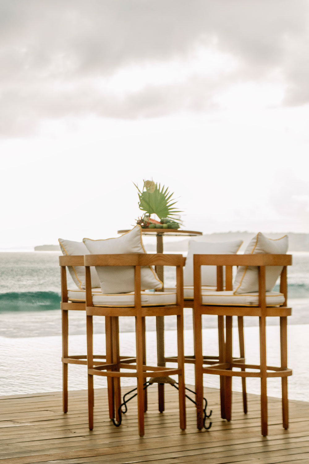 High table and stools on the timber pool deck facing the surf at NIHI Sumba, Sumba