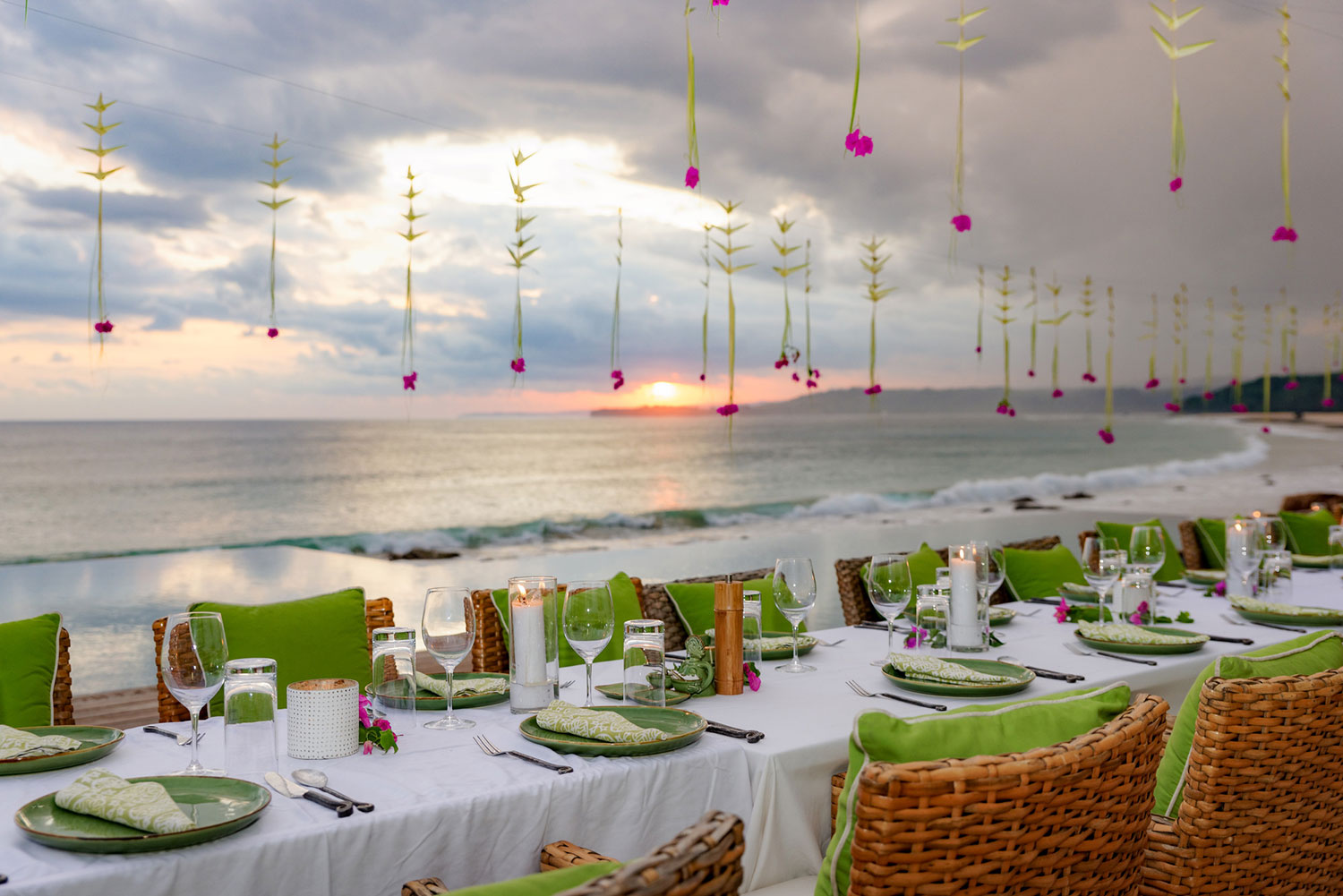 Long reception table set beside the infinity pool at sunset with hanging heliconia at NIHI Sumba, Sumba