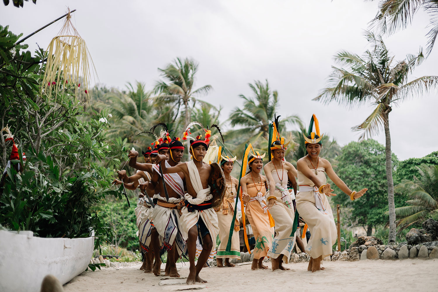 Sumbanese dancers in ceremonial headdresses processing along the beach at NIHI Sumba, Sumba