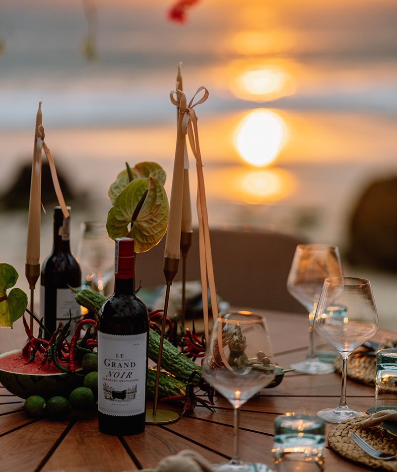 Candlelit dinner table with the sun setting over the ocean behind it at NIHI Sumba, Sumba