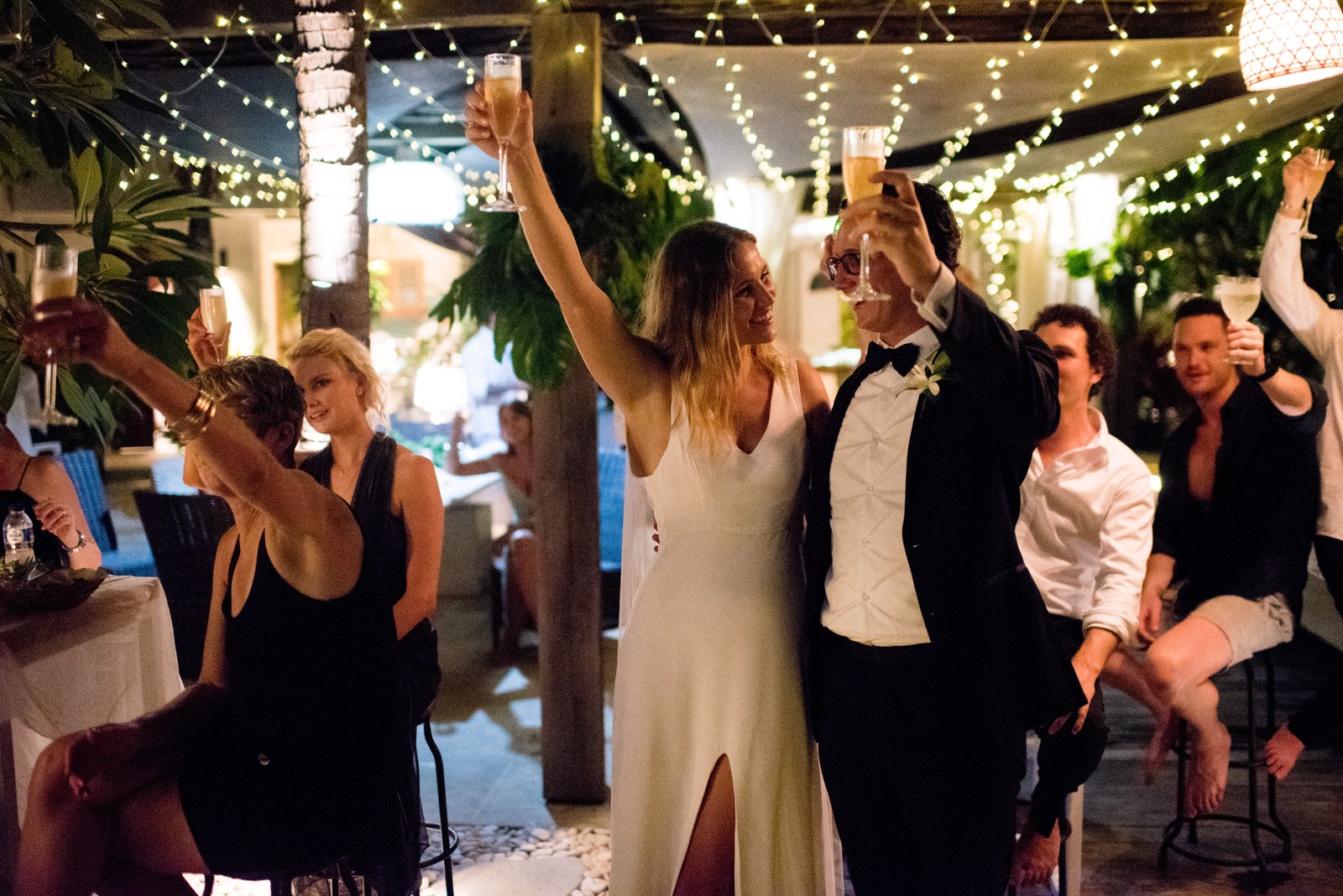 Wedding party celebrating under strings of fairy lights at Ohana's Beachfront Resort & Beach Club on Nusa Lembongan, Bali