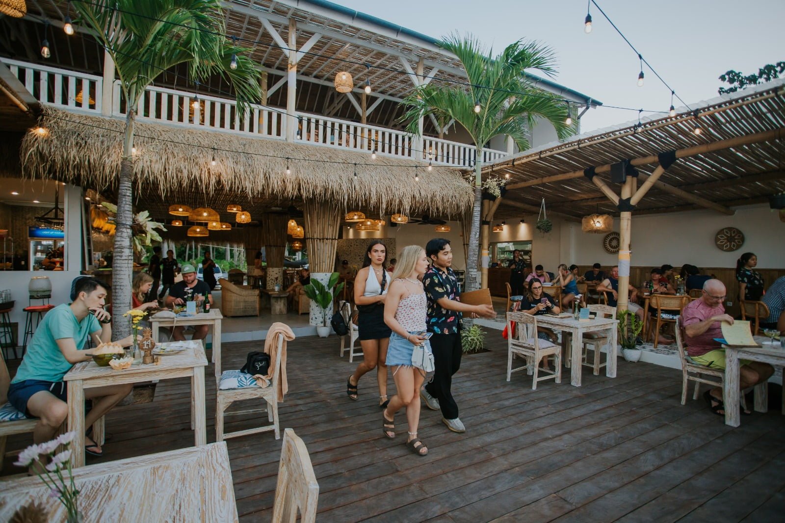 Open dining deck under thatch and string lights at dusk at Penida Colada on Nusa Penida, Bali