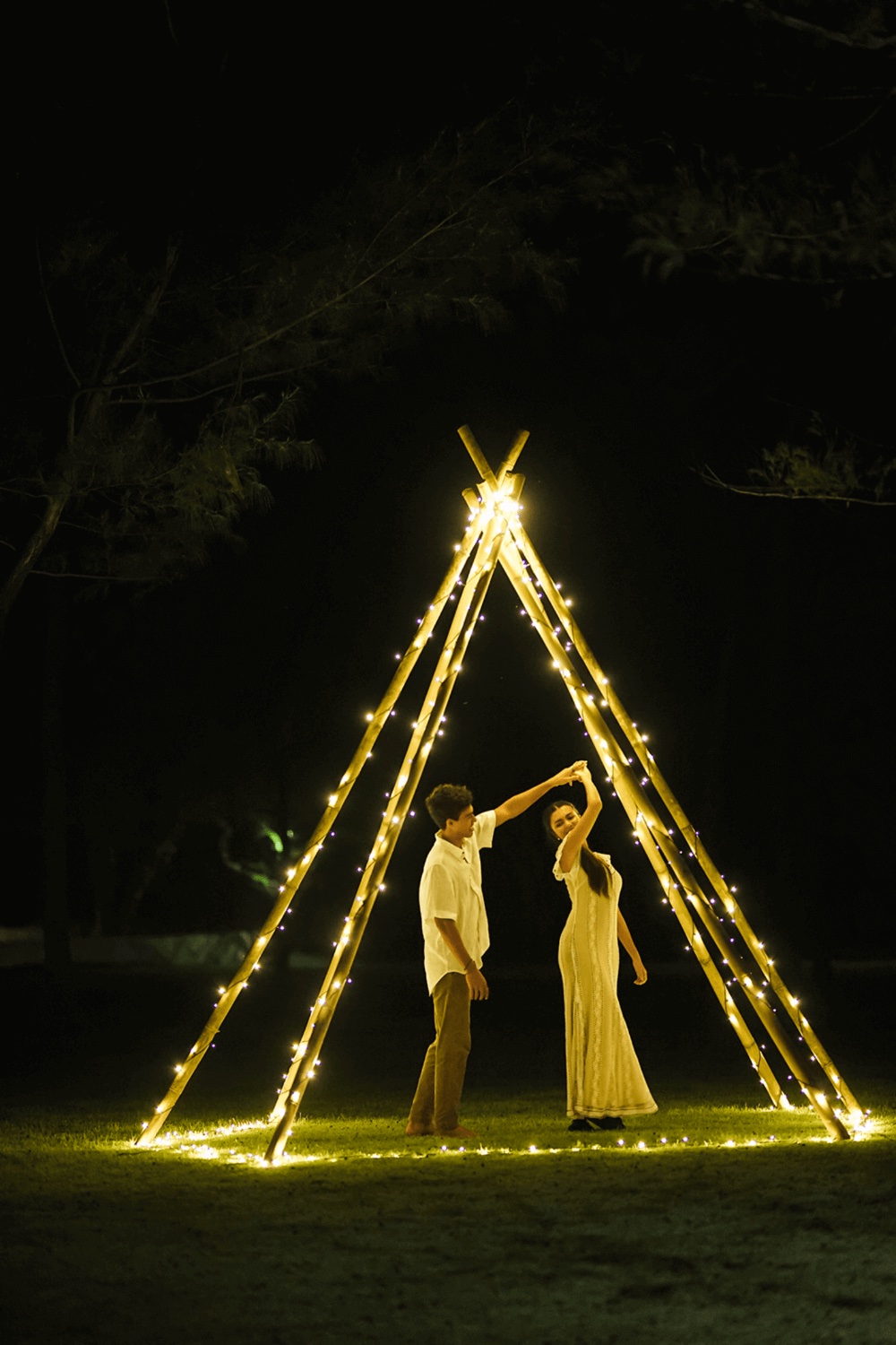 Couple dancing under a lit bamboo frame on the garden lawn at night at Pondok Santi Estate, Gili Trawangan