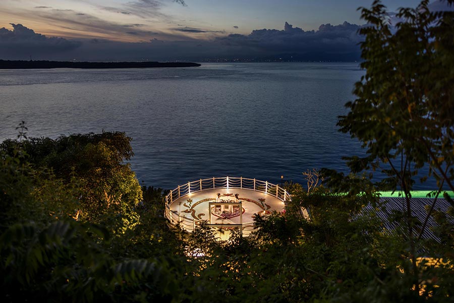 The Natura Chapel deck lit at dusk on the cliff above the water at Pramana Natura Nusa Penida, Bali