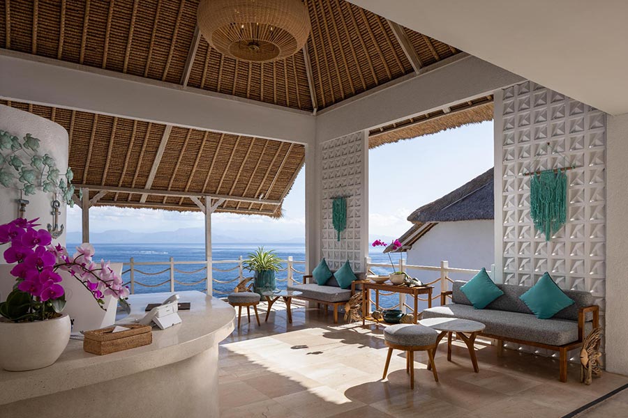 Open-air arrival lounge with orchids and a view over the water at Pramana Natura Nusa Penida, Bali