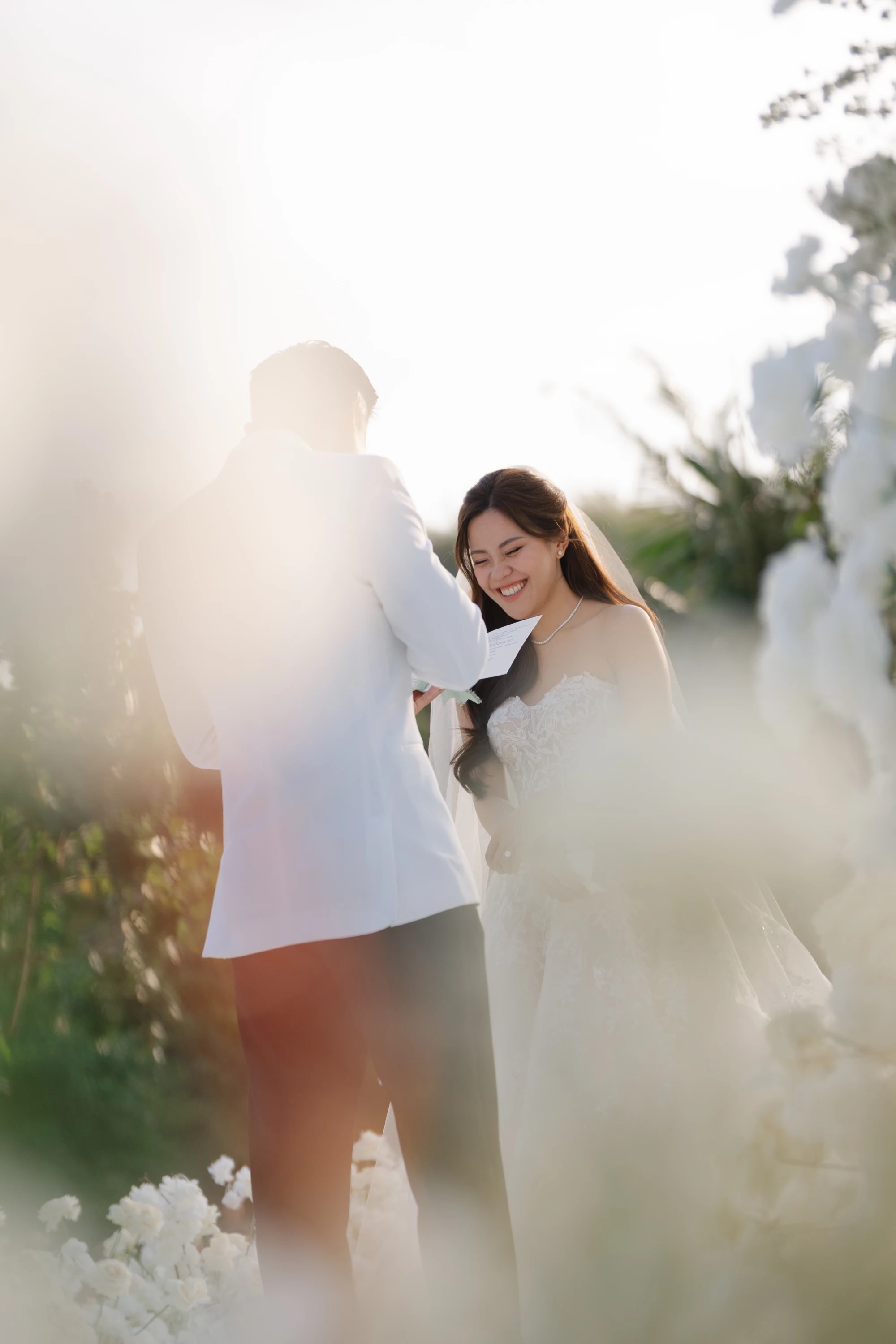A bride and groom at their wedding at Raffles Bali, backlit by the late sun