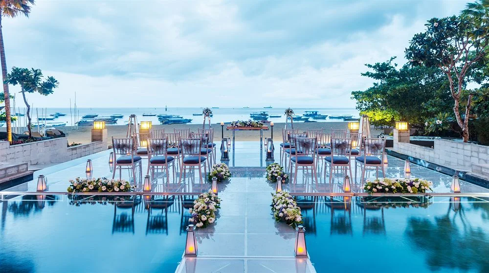 Water wedding set up on a glass aisle over the reflection pools at The Sakala Resort Bali, facing Tanjung Benoa Beach at dusk