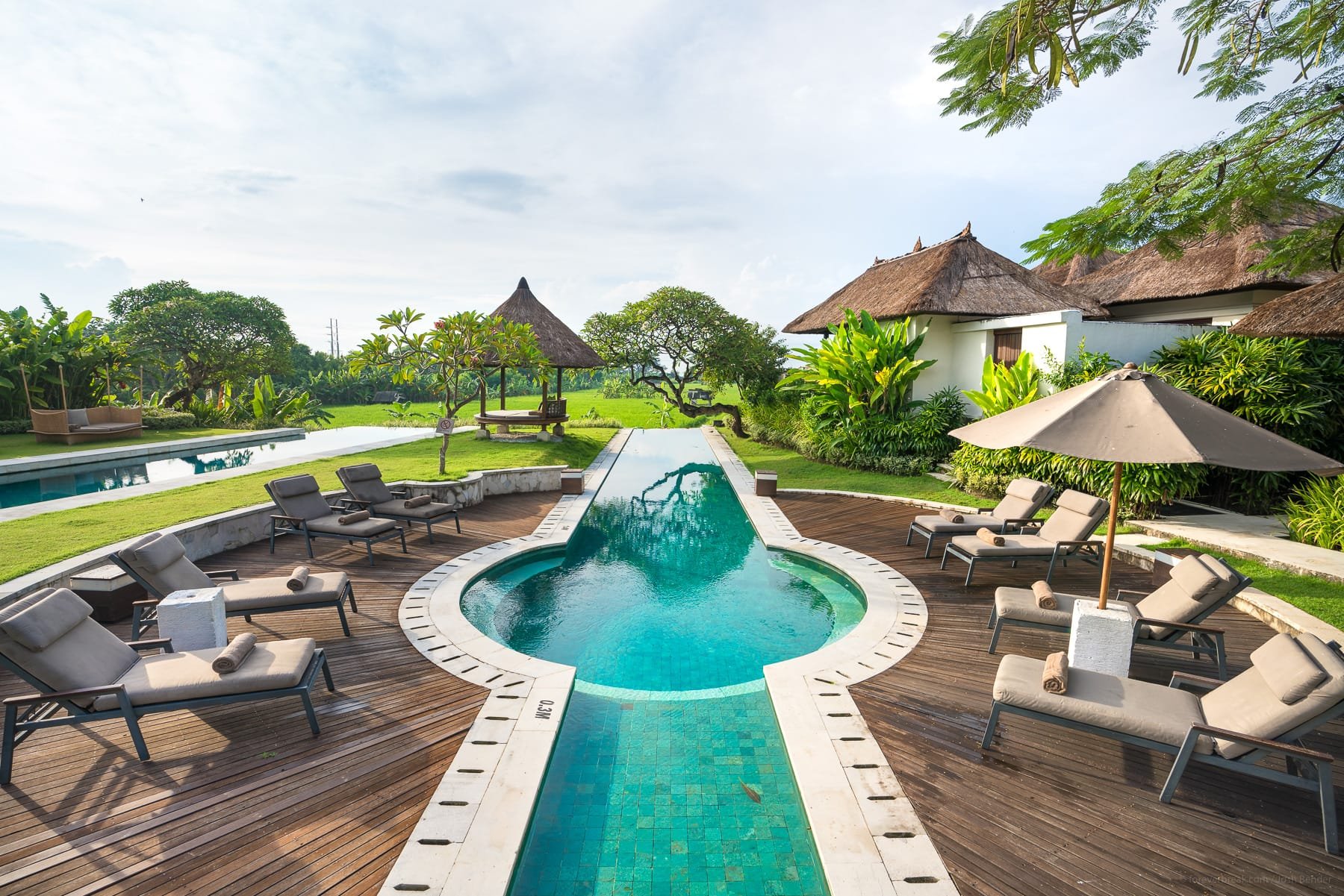 Pool deck, thatched pavilions, and rice-field views at The Samata near Sanur