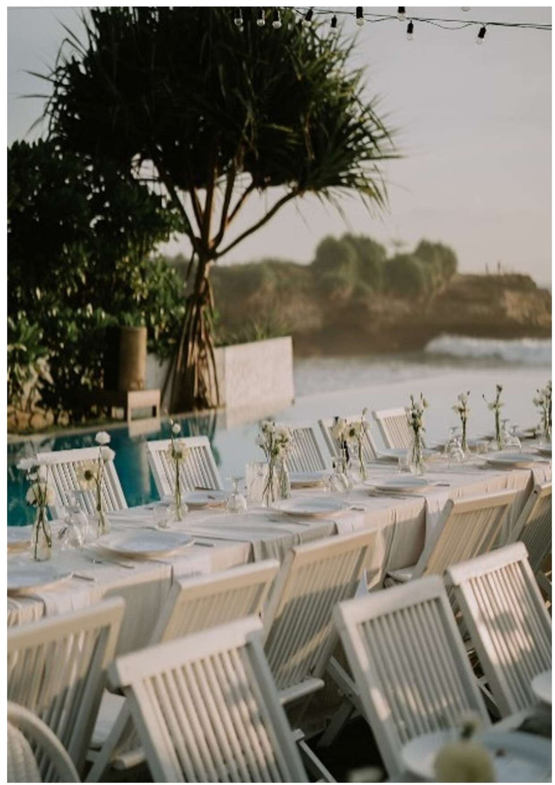 Long wedding table set beside the beachfront pool at golden hour at Sandy Bay Beach Club on Nusa Lembongan, Bali