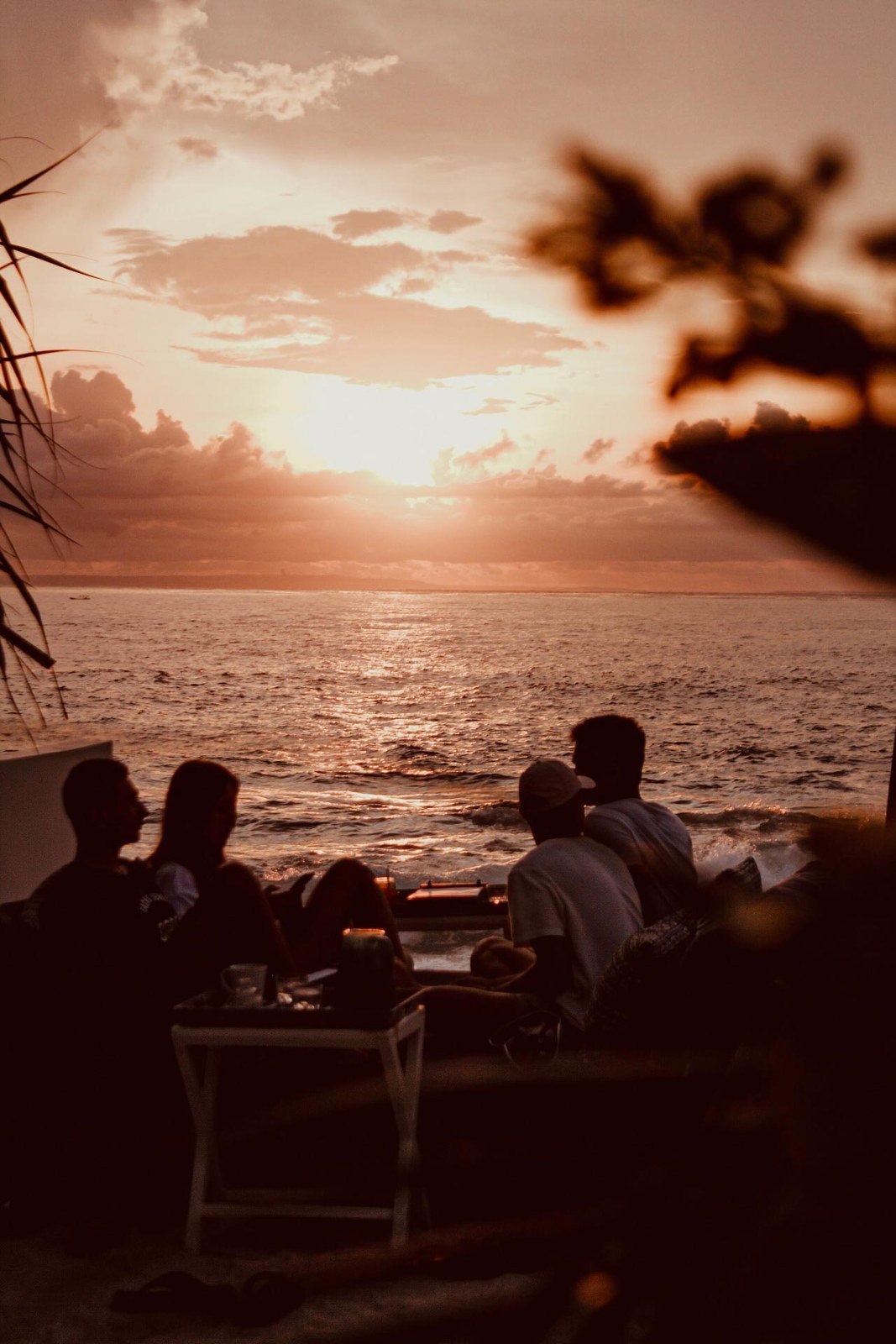 Guests dining at sunset at the water's edge at Sandy Bay Beach Club on Nusa Lembongan, Bali