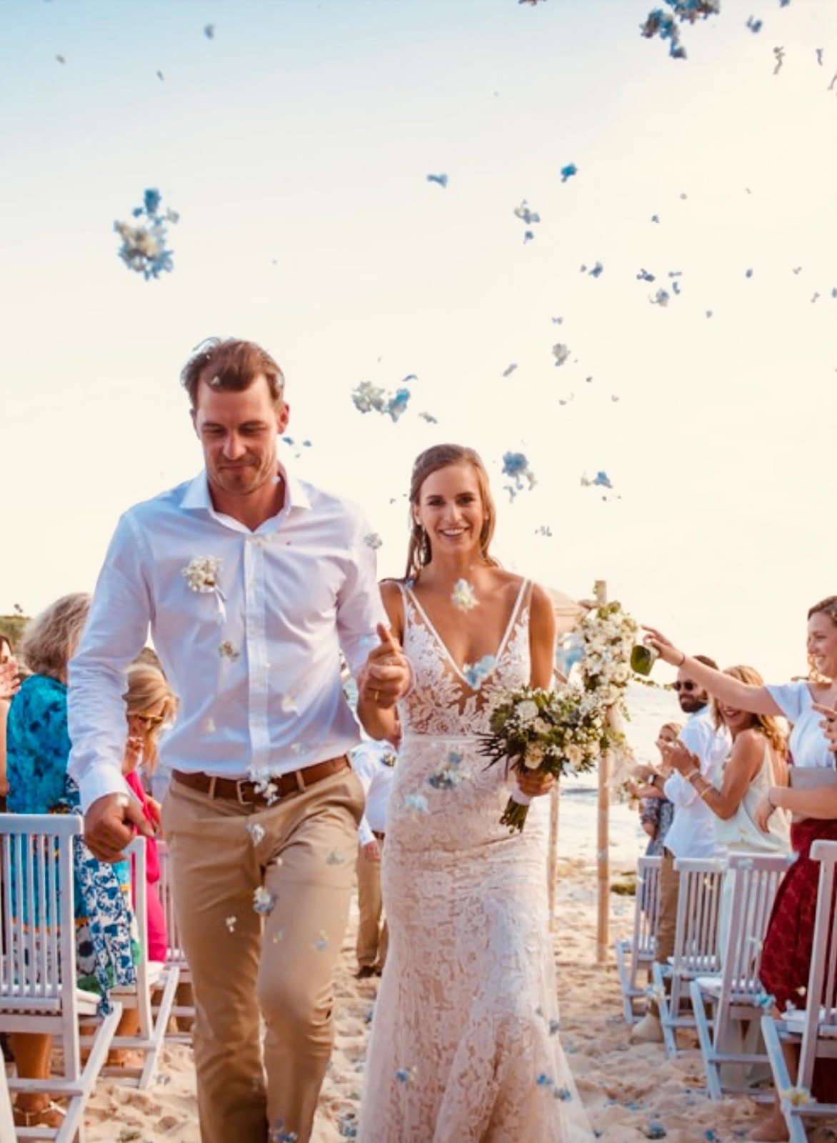 Bride and groom walking back down the aisle through confetti on the sand at Sandy Bay Beach Club, Nusa Lembongan, Bali